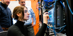 A QIS scientist adjusts electronics while two other researchers look on.